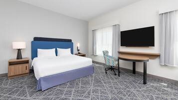 A hotel room with a bed, a desk, a TV, and a chair.