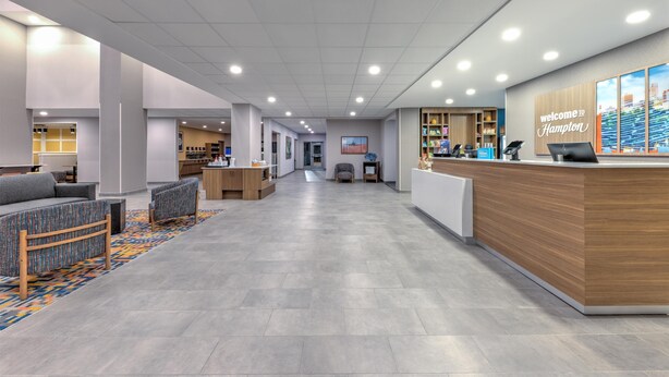 A modern lobby with a reception desk, seating area, and a view of the cityscape. - Hampton Inn & Suites Little Rock Airport (Little Rock)