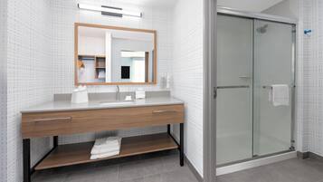 Ein modernes Badezimmer mit einem Holzbadschränkchen, einer Duschkabine aus Glas und Wandverkleidung mit Muster.