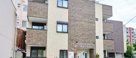 Un edificio residencial de varios pisos con un letrero que dice "Miyoshi House".