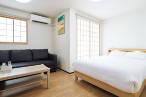 A modern hotel room with a bed, a sofa, a table, and a window. - Miyoshi House Nonsmoking Self Checkin (Osaka)