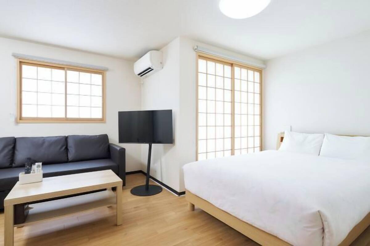 A room with a bed, a sofa, a coffee table, and a floor lamp.