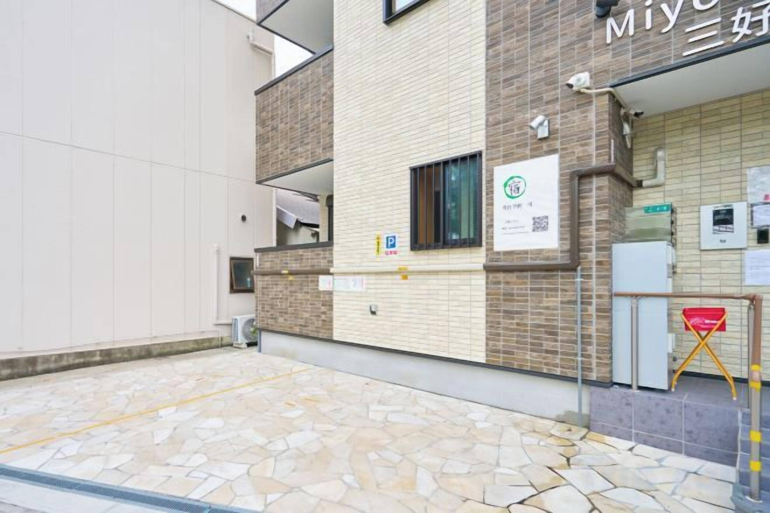 Un bâtiment dont le rez-de-chaussée est recouvert de pierres, avec un mur en briques et une enseigne arborant un logo vert.