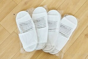 Four pairs of white slippers with text on them, placed on a wooden floor. - Miyoshi House Nonsmoking Self Checkin (Osaka)