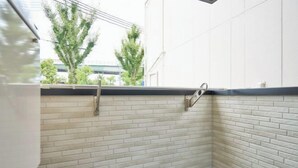 A corner of a room with white brick walls, a metal towel rack, and a window overlooking greenery. - Miyoshi House Nonsmoking Self Checkin (Osaka)