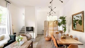 A modern living room with a wooden dining table, leather sofa, and a TV. - Treehouse studio, secluded & chic hiker’s paradise

 (San Anselmo)