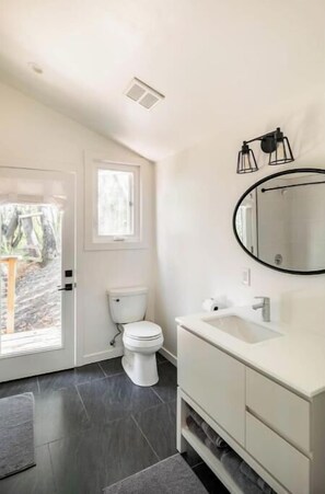 A modern bathroom with a toilet, sink, and mirror. - Treehouse studio, secluded & chic hiker’s paradise

 (San Anselmo)