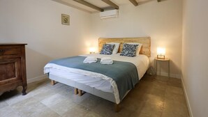 A bedroom with a bed, bedside lamps, a wooden dresser, and a picture on the wall.