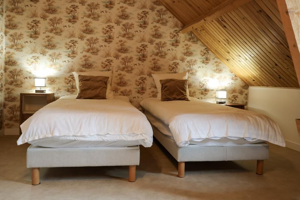 Un dormitorio con dos camas, cabeceros de madera y techo inclinado.