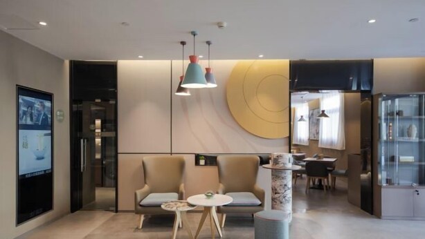 Una hall moderna con un'area salotto, un tavolo rotondo e una colonna decorativa.