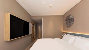 Una moderna camera d'hotel con un ampio letto, una TV a parete e un decoro circolare al muro.