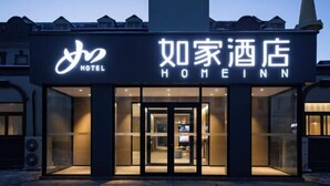 Ingresso di un hotel dal design moderno, con porta in vetro e insegna illuminata.