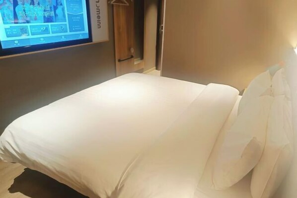 Quarto de hotel com uma cama, uma tela de TV e um guarda-roupa.