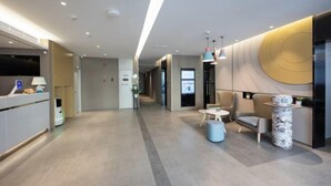 Una hall d'albergo moderna con una reception, una zona salotto e un'ampia parete con un motivo circolare.