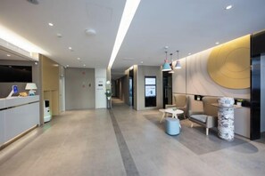 A modern hotel lobby with a reception desk, seating area, and a large wall with a circular design. - Homeinn Hotel (Beijing ABP World Park Guogongzhuang Subway Station) (Beijing)