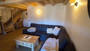 A cozy living room with a dark sofa, a wooden coffee table, and a staircase. - Duplex apartment valley view 4 Bdrm, 3 bed covered parking center of La Rosière (La Rosière)