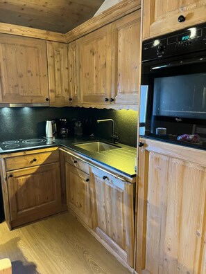 A kitchen with wooden cabinets, a stainless steel sink, and a black microwave. - Duplex apartment with a view of the valley, 4 bedrooms, 3 beds, covered parking, downtown La Rosière (La Rosière)