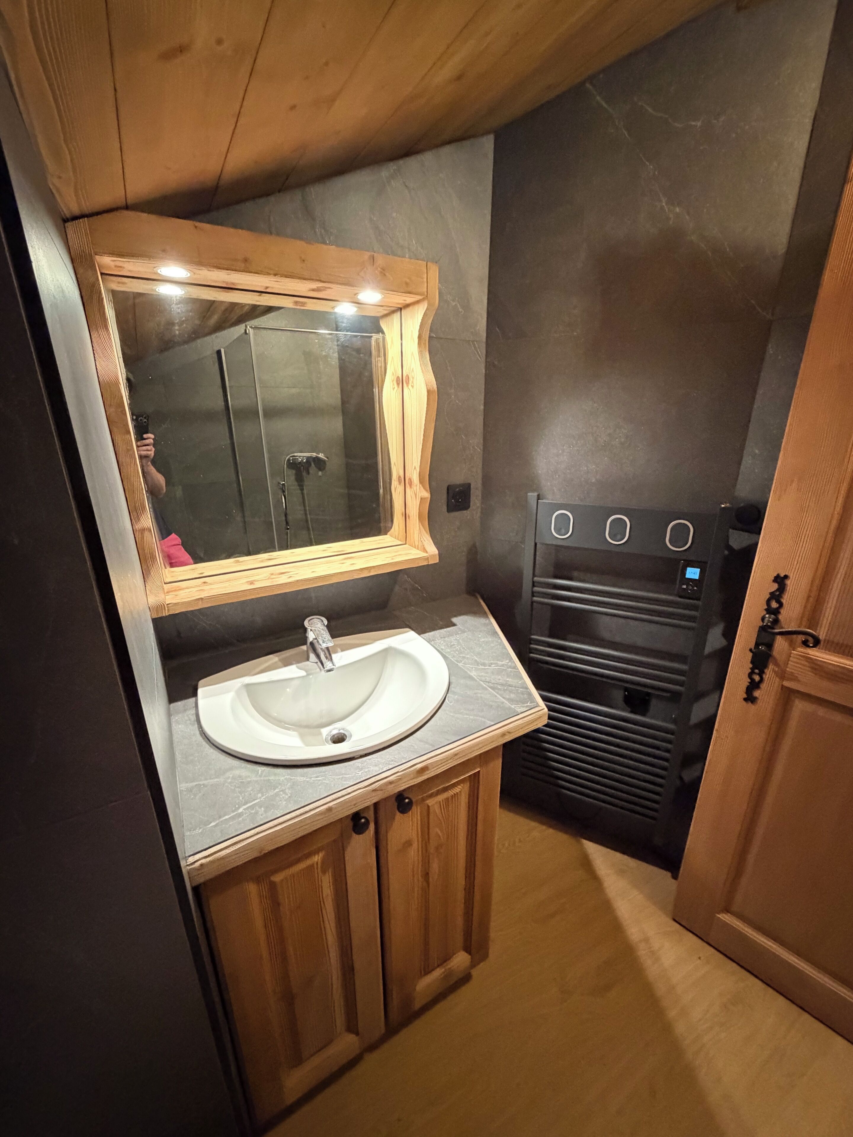 Un baño pequeño con un tocador de madera, un lavabo blanco y un espejo.