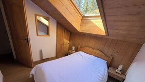 A bedroom with a sloped ceiling, a bed, a nightstand, a wooden wardrobe, and a mirror. - Duplex apartment valley view 4 Bdrm, 3 bed covered parking center of La Rosière (La Rosière)