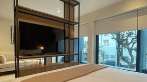 A modern hotel room with a large bed, a flat-screen TV mounted on a wooden frame, a sofa, and a balcony with a view of the city. - Liven in Miraflores by Wynwood House (Lima)