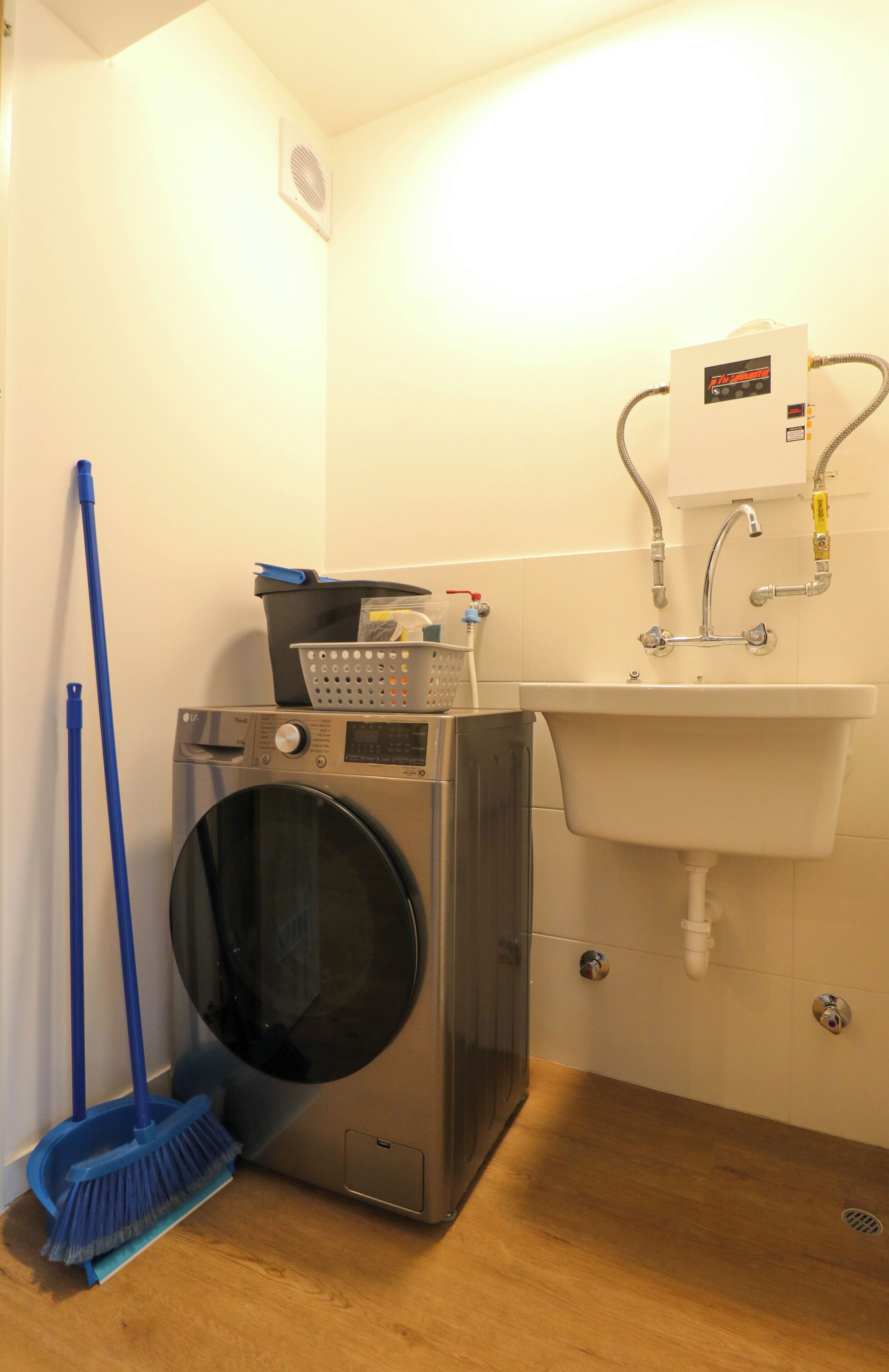 A laundry area with a washing machine, a sink, and a mop.