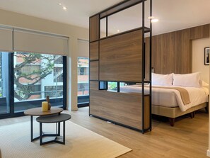 Un dormitorio moderno con una cama grande, un separador de madera y vistas al exterior.