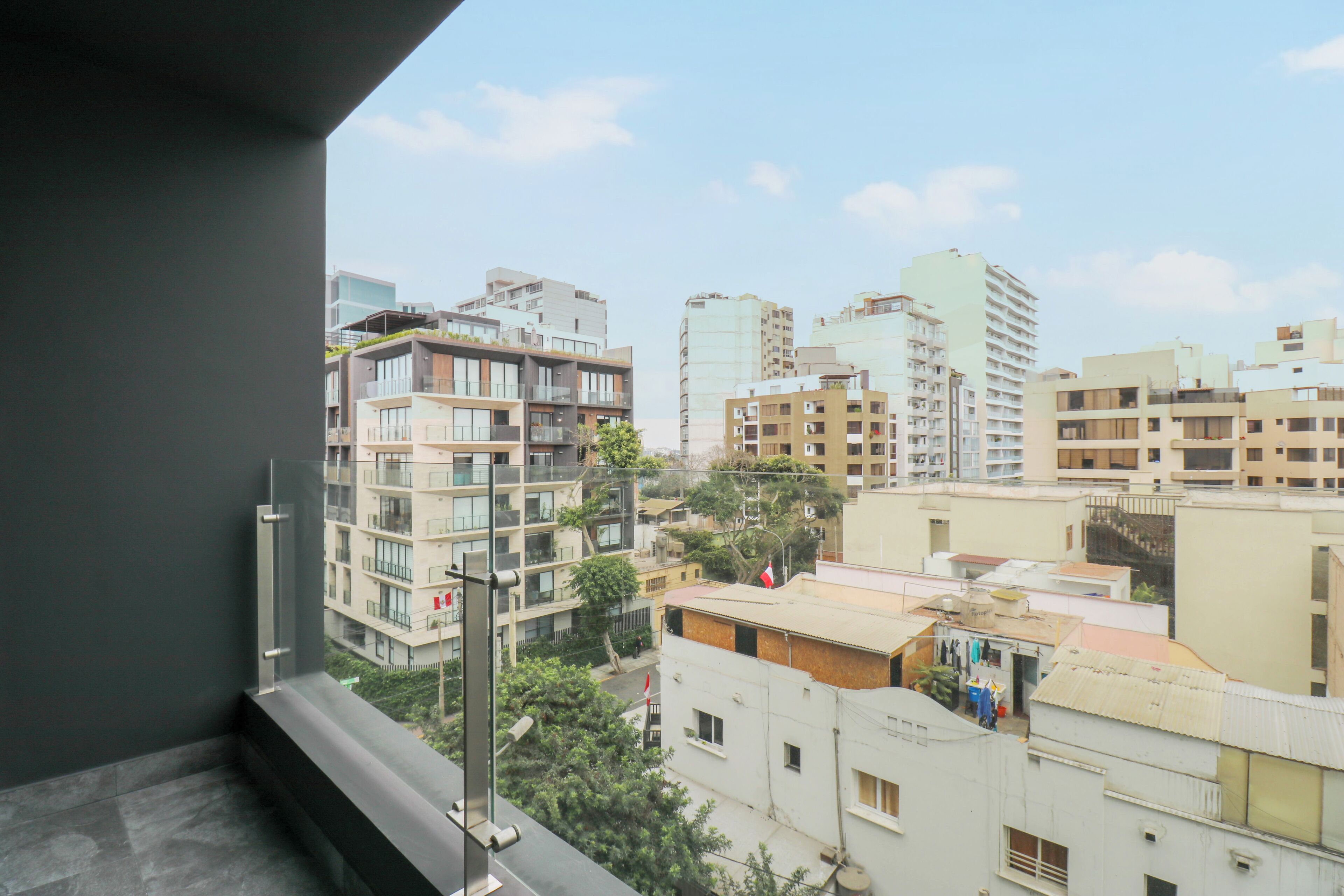 A high-rise building with multiple balconies and a view of surrounding buildings.