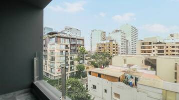 A high-rise building with multiple balconies and a view of surrounding buildings.