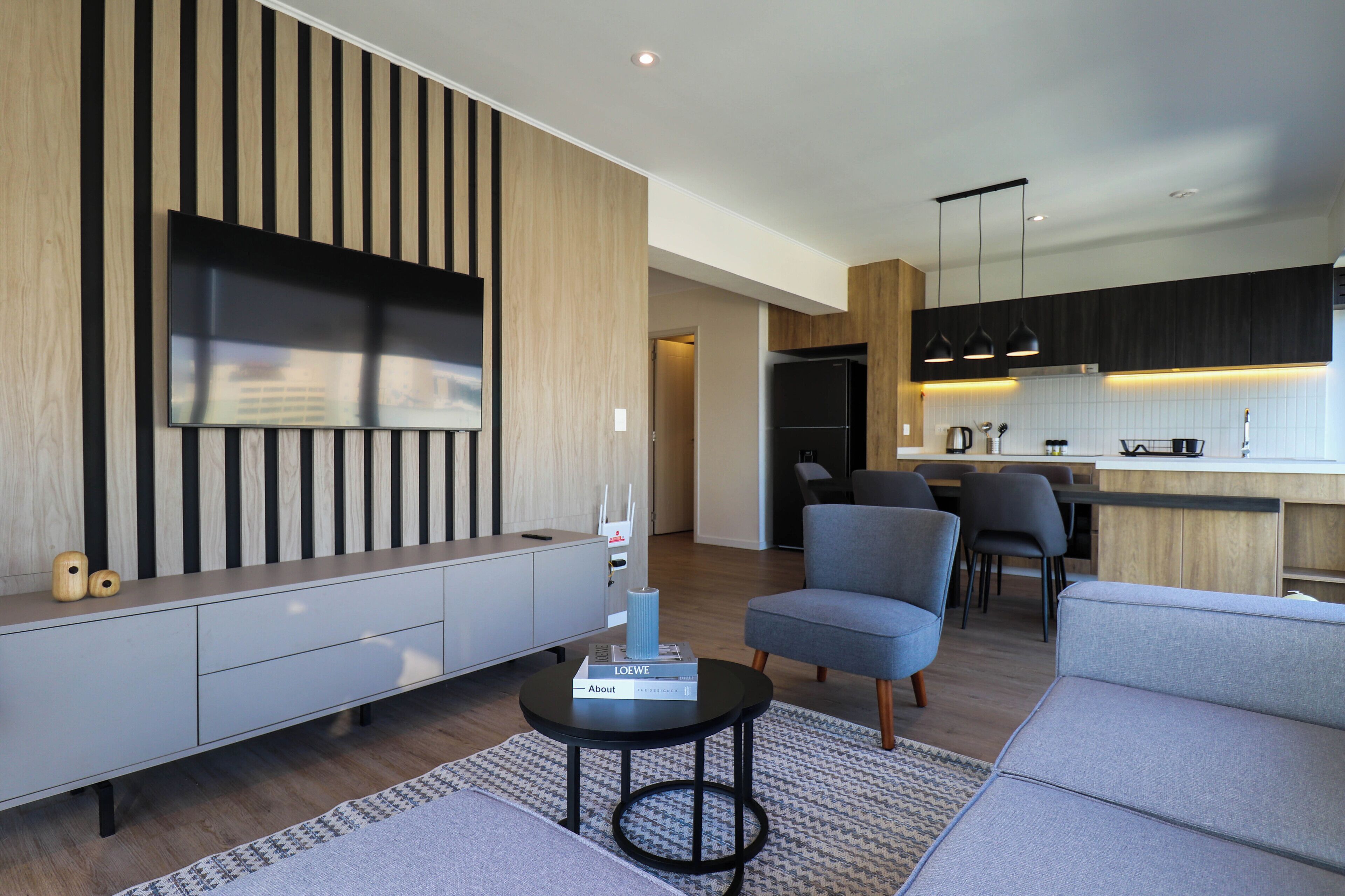 A modern living room with a flat-screen TV, grey sofa, and a coffee table.