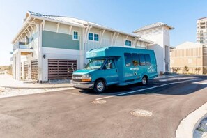 A turquoise van parked in front of a modern building with a garage. - Cozy & Bright Townhome w/EV Charger-Walk to Beach (Perdido Key)