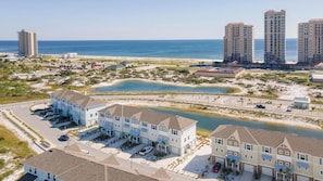 A coastal residential area with beachfront properties, a marina, and high-rise buildings in the background. - Cozy & Bright Townhome w/EV Charger-Walk to Beach (Perdido Key)