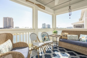 A covered outdoor seating area with wicker furniture, a small table, and a hanging light fixture. - Cozy & Bright Townhome w/EV Charger-Walk to Beach (Perdido Key)