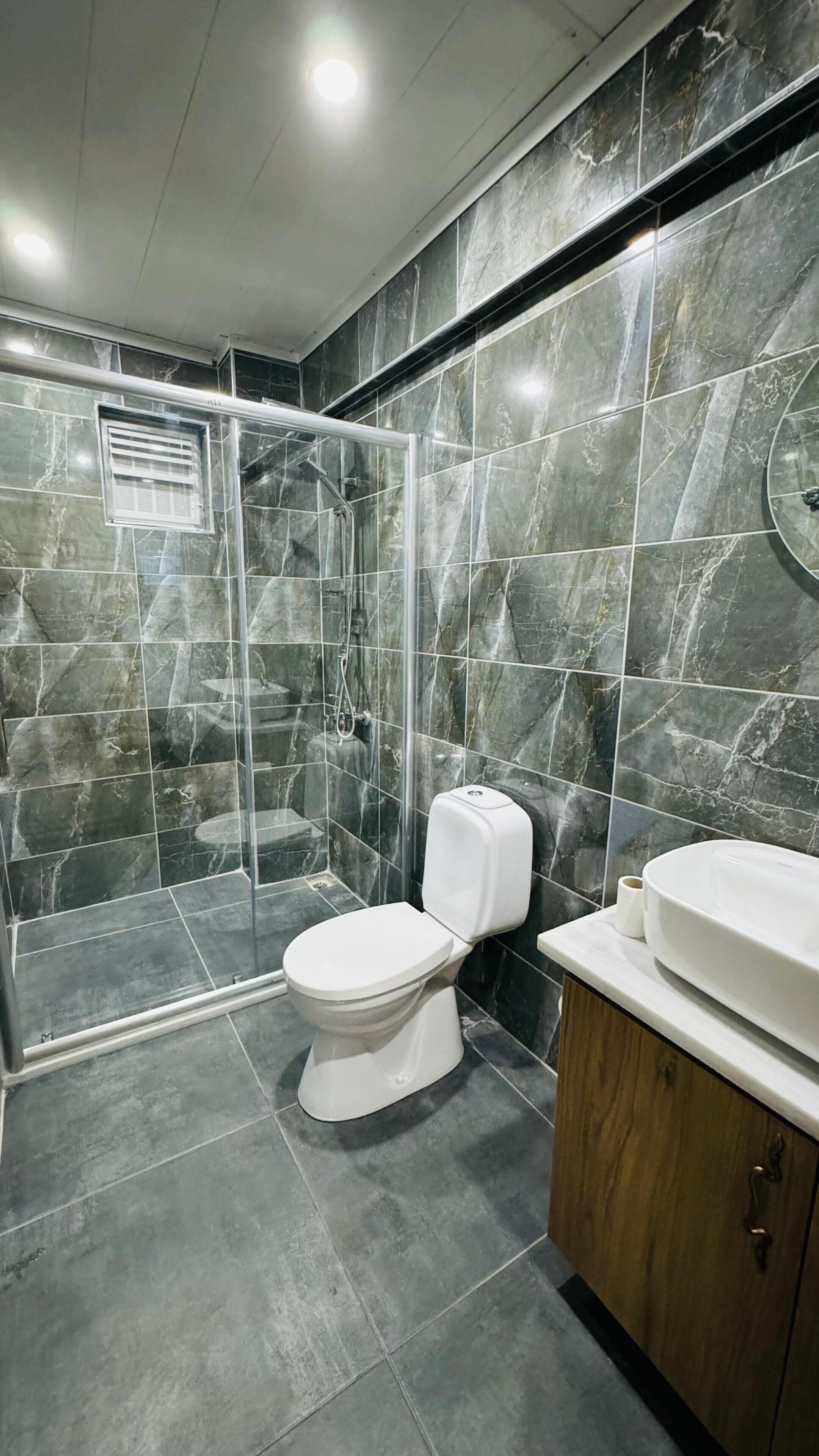 A bathroom with a shower enclosure, a toilet, and a vanity with a sink.