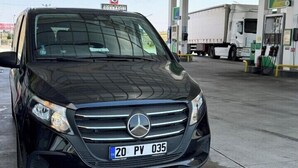 A black Mercedes-Benz SUV parked at a gas station with a clear sky and a red flag in the background. - Akapella (Denizli)