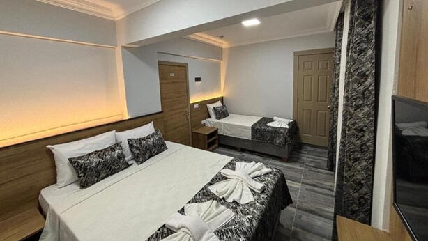 A hotel room with two beds, a TV, and a bathroom. - Akapella (Denizli)