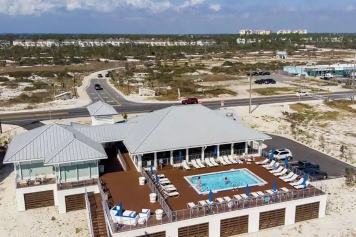 A cruise ship with a pool area, lounge chairs, and a covered deck.