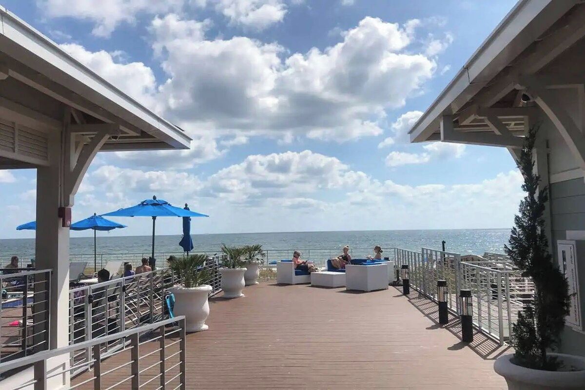 Eine Terrasse mit Sitzgelegenheiten und Sonnenschirmen mit Blick auf das Meer.