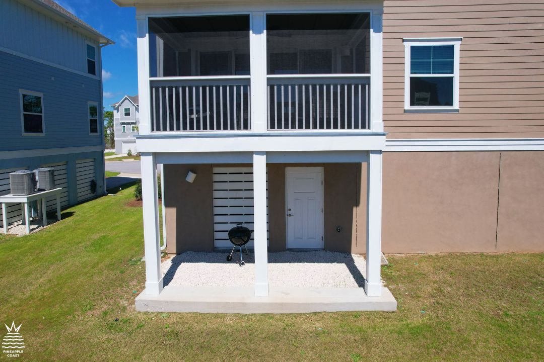 A two-story residential building with a balcony, a front door, and a grill area.