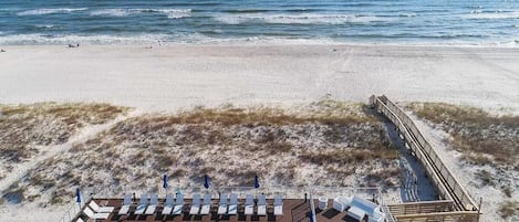 A pool area with a view of the ocean, deck chairs, and a wooden deck.