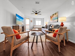 A living room with a sofa, two armchairs, a coffee table, and a television. - Sunset Harbor Condo w/Balcony, Fishing Pier & Pool (Navarre)