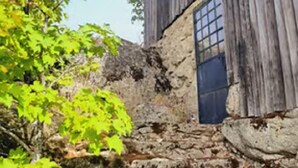 Un edificio rústico de piedra con fachada de madera, una ventana y una puerta.