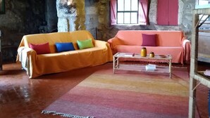Una habitación rústica con paredes de piedra, techo de madera y dos sofás con cojines de colores.