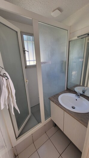 A bathroom with a glass shower enclosure, a white sink, and a mirror. - Vvf Villages Sigean (Sigean)