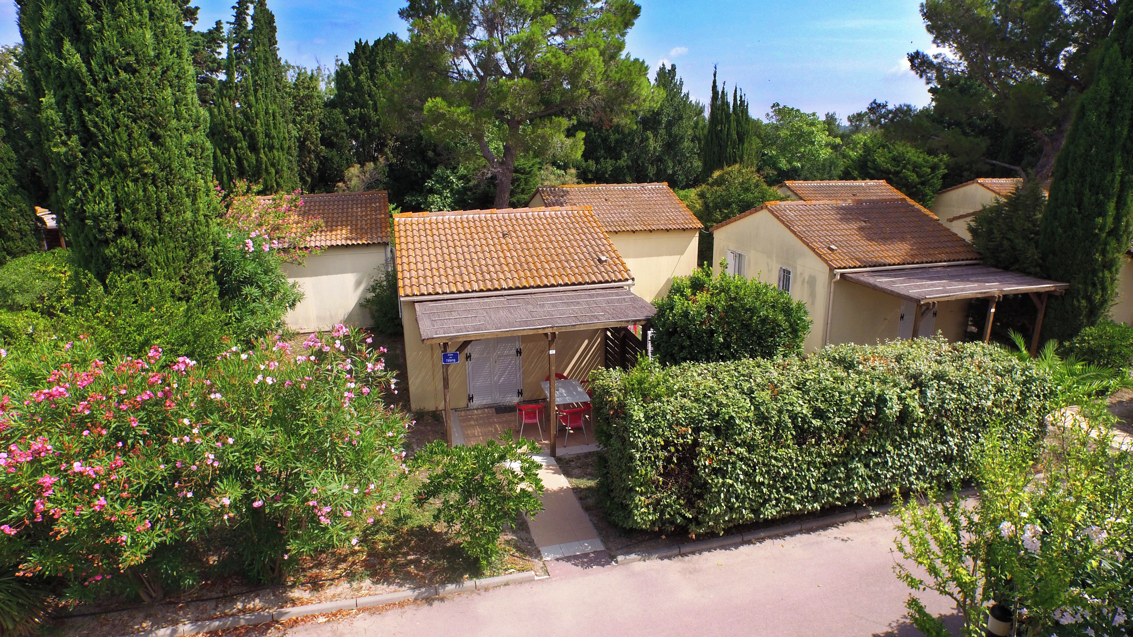 Une rangée de charmantes maisons de style méditerranéen, avec des toits en tuiles, entourées d’une végétation luxuriante et de plantes en fleurs.