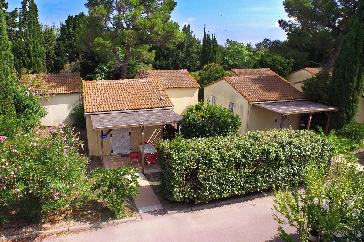 A row of Mediterranean-style cottages with tiled roofs, surrounded by lush greenery and flowering plants.