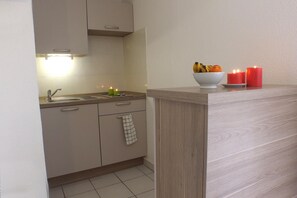 A kitchen with a sink, cabinets, and a countertop. There are candles and a bowl of fruit on the counter. - Vvf Villages Sigean (Sigean)