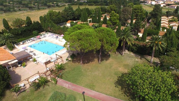 An aerial view of a residential area with a swimming pool surrounded by trees and houses. - Vvf Villages Sigean (Sigean)