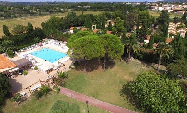 Vista aérea de una zona residencial con piscina rodeada de árboles y casas.