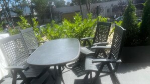 An outdoor patio with a round table and four chairs, surrounded by greenery and trees. - Apartamenty na Wydmach BR (Międzywodzie)