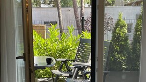A room with a sliding glass door leading to an outdoor patio area with a table, chairs, and a patterned rug. - Apartamenty na Wydmach BR (Międzywodzie)